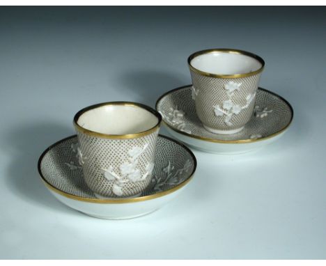 A pair of Capodimonte gold mounted and stippled white tea bowls and saucers, the gold stippling on each around moulding in re