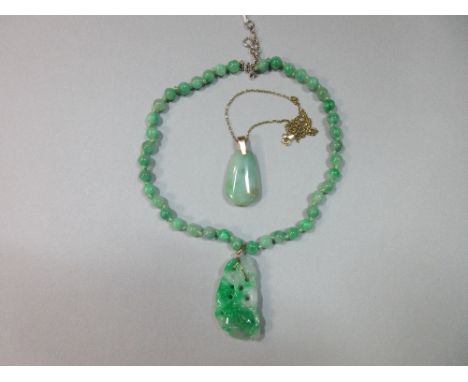 A carved jade pendant on a jade bead necklace together with a jade pendant on gold chain, the first pendant a pierced emerald