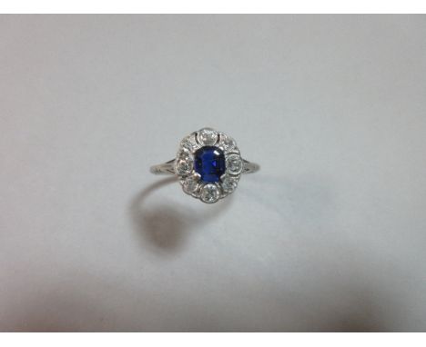 An early 20th century sapphire and diamond cluster ring, the rectangular step cut sapphire in a delicately pierced surround o