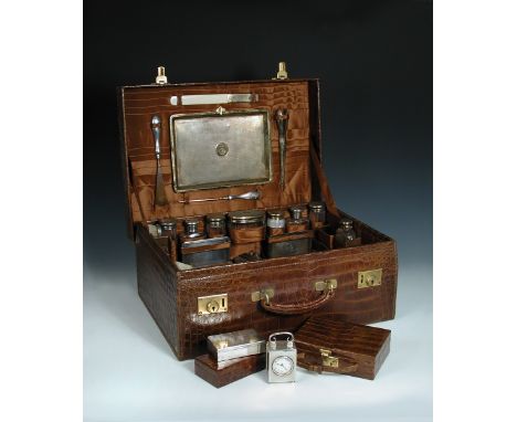 A lady's crocodile leather travelling case, extensively fitted with silver mounted dressing table utensils by John Collard Vi