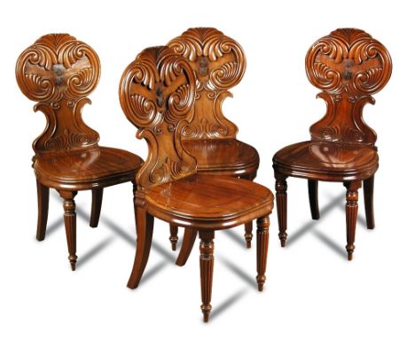 A set of four William IV mahogany hall chairs, with boldly carved c-scroll backs centred in relief by the arms of the Neave f