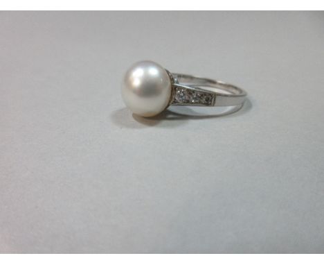 An 18ct gold pearl and diamond ring, the slightly bouton 10.8mm white pearl cup set to a tapered shank with integral shoulder