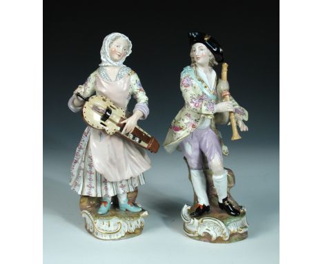 A pair of late 19th century Meissen figures of musicians, after J J Kaendler, they stand on Rococo bases smiling towards each