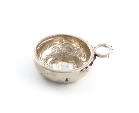 An early 19th century French silver wine taster, marks worn, circular form, the bowl set with a coin, stylised double snake r