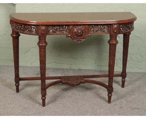 A heavily carved mahogany console table featuring floral motifs. Approx. dimensions 120cm x 44cm x 81cm.  