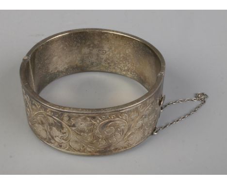 A silver bangle engraved with floral decoration. Hallmarked Birmingham 1957 by Joseph Gloster Ltd. Total weight 36.92g.  