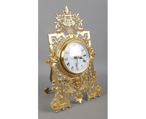 A brass easel desk clock, with pierced scrolled and floral front. Height: 31cm. Fitted with later quartz movement.  Repair to