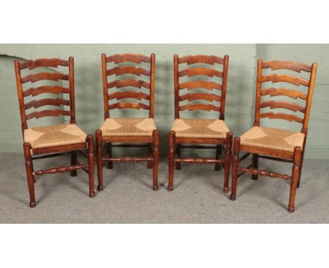 A set of four oak ladder back dining chairs, with rush bases.  One chair loose.