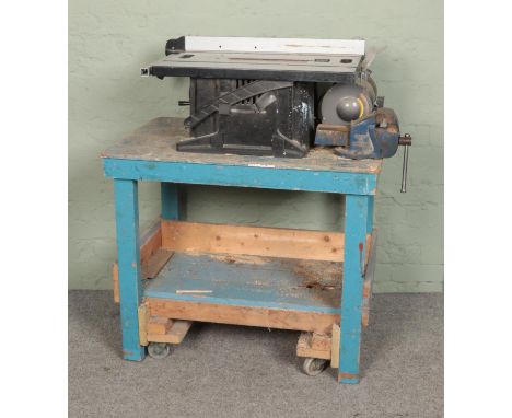 A small wooden work bench with table saw, bench grinder and vice.  