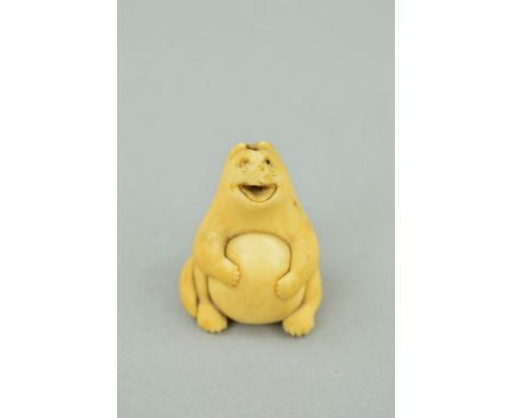A MEIJI PERIOD CARVED IVORY NETSUKE, in the form of a stylised cat or fox holding a large egg against its body, bears charact