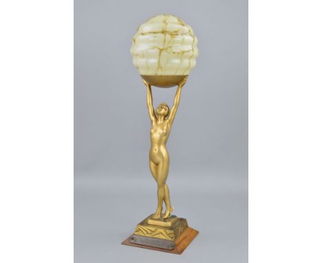 AN ART DECO NUDE FIGURAL LAMP, the female figure is holding aloft a smoke glass pattern shade, signed Limousin to the base of