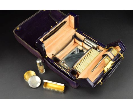 A GEORGE V TRAVELLING VANITY CASE RETAILED BY J.C. VICKERY, purple canvas outer cover with velvet lining embossed with gilt i