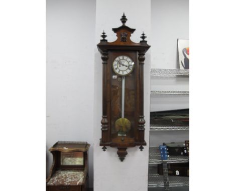A XIX Century Walnut Vienna Wall Clock, with applied top, finial decoration and white enamel dial, Roman numerals and two bra