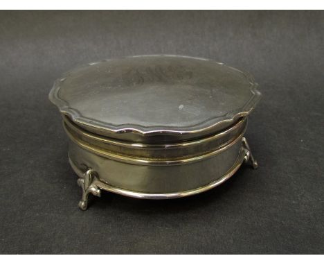 A silver circular footed trinket box, raised on three feet, Birmingham 1921, monogrammed, dented