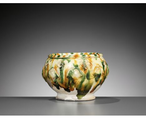 A SANCAI-GLAZED APPLIQUE-DECORATED POTTERY JAR, TANG DYNASTYChina, 618-907. Rising from a splayed foot to a short rim, the si