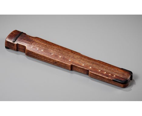 A WOOD 'QIN' WRIST REST, QING DYNASTYChina, 1644-1912. Carved as a qin supported on four short feet, inlaid with silver wire 