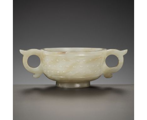 A PALE CELADON JADE WINE CUP, MING DYNASTYChina, 1368-1644. The rounded sides rising from a short foot, carved in relief with