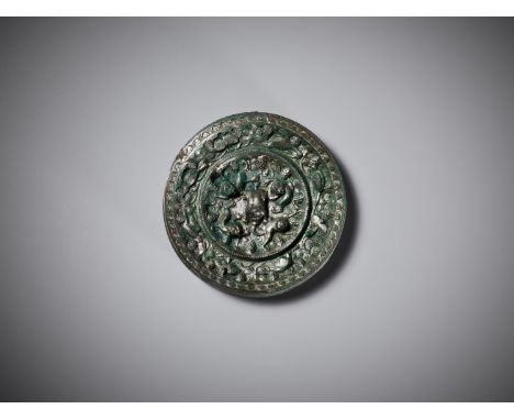 A SILVERY BRONZE 'LION AND GRAPEVINE' MIRROR, TANG DYNASTYChina, 618-907. Of circular form, the back cast in high relief, the