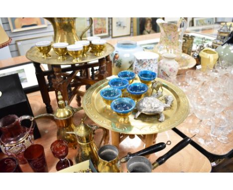 A Persian brass Dallah coffee pot and two smaller examples, two small eastern brass tray-topped tables, lined brass cups and 