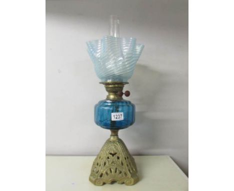 A Victorian oil lamp with blue glass font and original blue swirl shade on a cast iron base.