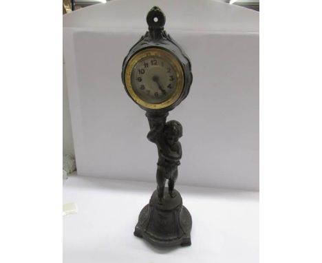A spelter figure of a cherub supporting a clock.