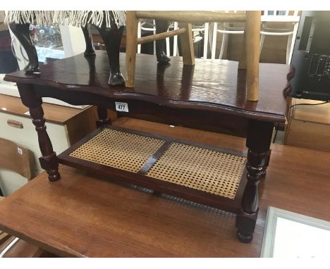 A dark wood stained coffee table with cane shelf.