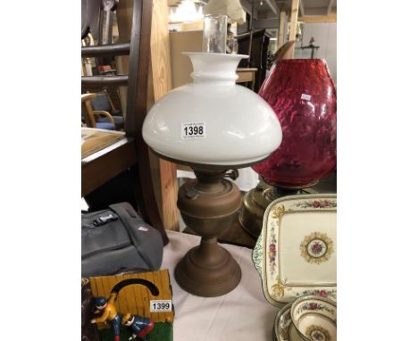 A brass oil lamp with white mushroom shade.