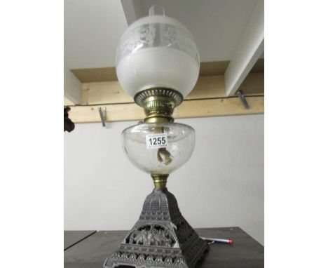 A Victorian oil lamp on cast iron base with glass font and later etched glass shade.