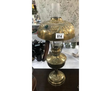 A brass oil lamp with impressed holly decoration and jewels in shade.