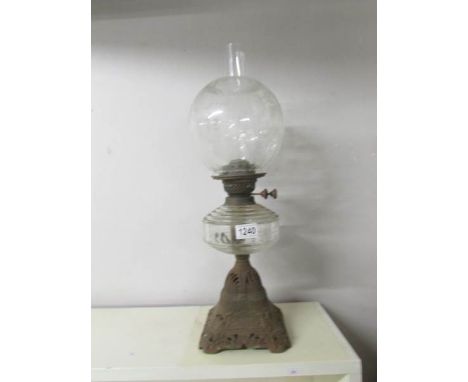 A Victorian oil lamp with clear glass font and floral acid etched shade on a cast iron base.