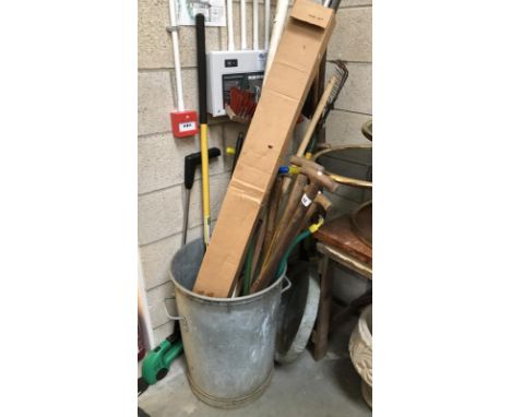 A galvanised dustbin and garden tools.