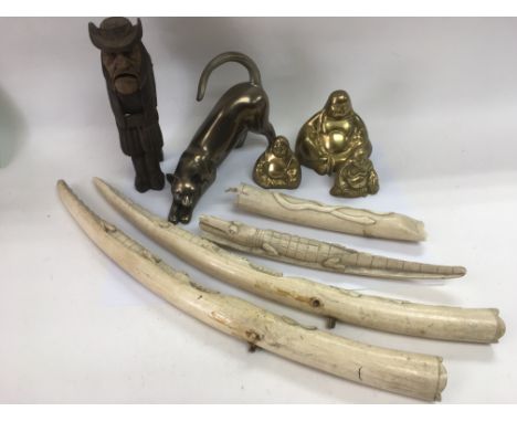 A collection of oddments comprising three brass Buddhas, a wooden nutcracker, three carvings and a modern ornament of a cat.