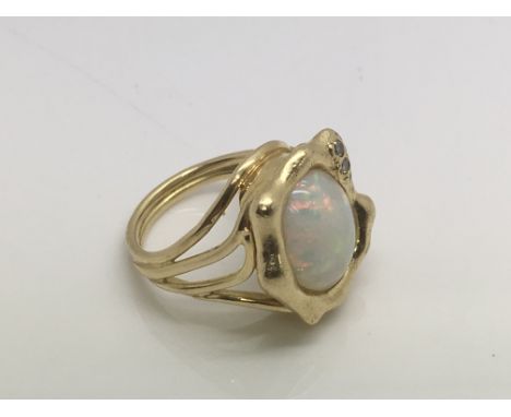 An unmarked gold ring set with a central opal and two small diamonds in a modernist 60s style setting, approx 10g and approx 