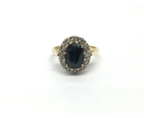 A ladies 18ct yellow gold ring set with a central dark sapphire surrounded by diamonds. Total weight approximately 4.3 grams,