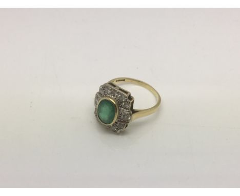 An 18ct gold ring set with a central emerald surrounded by small diamonds, approx 4.5g and approx size N.