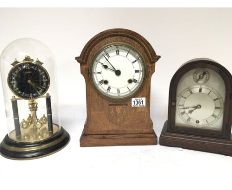 A collection of three clocks an Edwardian inlaid oak cased clock a small mantel clock with an arched silvered dial and and a 