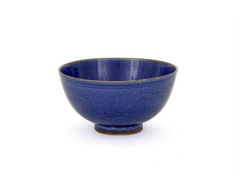 A Chinese blue glazed 'Dragon' bowl, circa 1645, incised to the exterior with two dragons chasing the flaming pearl, the base