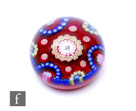 A later 20th Century Perthshire glass paperweight of domed form, internally decorated with a central cane depicting a stylise