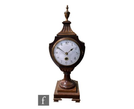 An Edwardian mahogany mantle clock in the Regency style, white circular dial with Arabic numerals, in a fluted urn shaped cas