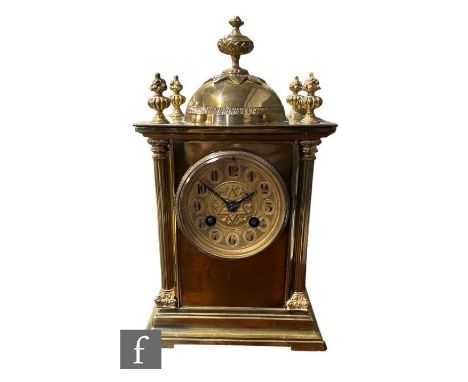 An early 20th Century brass mantle clock, eight day striking movement on a gong with Arabic dial below a dome, Corinthian pil