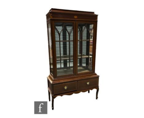 An Edwardian satinwood crossbanded and inlaid mahogany display cabinet enclosed by a pair of arch bar glazed doors below a ca