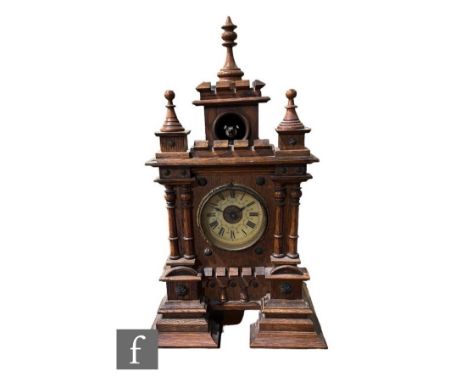 A 19th Century walnut cased cuckoo mantle clock of castellated and turned finial form, circular Arabic dial, stepped base, he