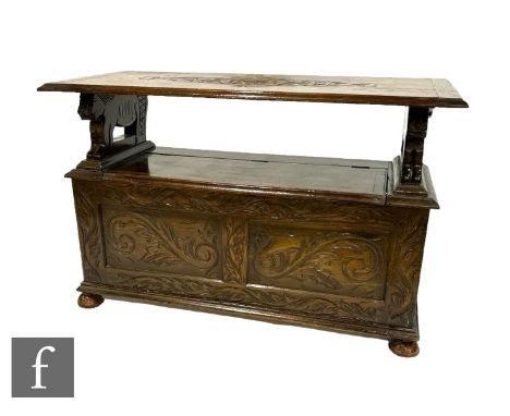 A Victorian style carved oak monk's bench, fold over top above a scroll decorated front, on ball feet, height 68cm x depth 48