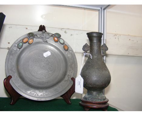 An antique 22cm diameter Chinese pewter plate with cabochon stone mount, together with an early Chinese bronze vase on wooden