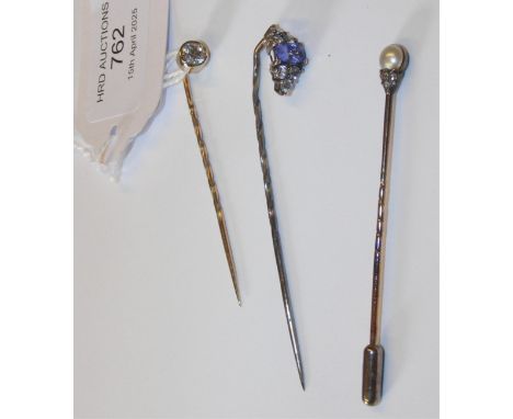 A diamond stick pin together with two others