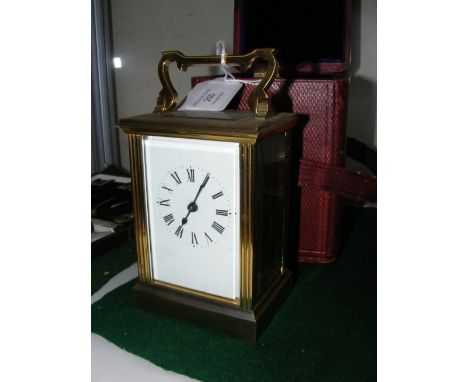 A 13cm high brass cased carriage clock with enamel dial and leather travelling case