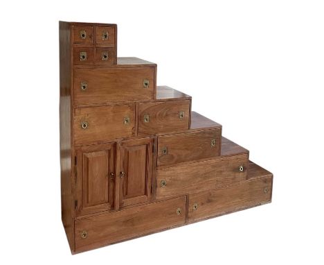 A modern teak stepped wall unit, with six tiers and campaign style brass handles, height 133cm, width 152cm.Condition Report: