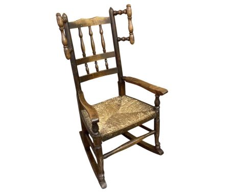 A chid's reproduction rush seated bobbin back rocking chair, height to seat 33cm, overall height 86cm.