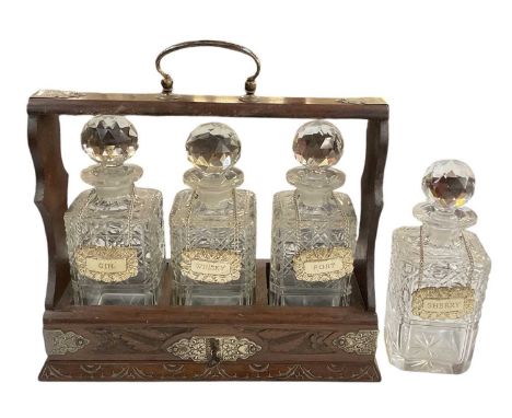 An early 20th century oak tantalus with silver plated mounts, with three cut glass decanters, each with silver plated label, 