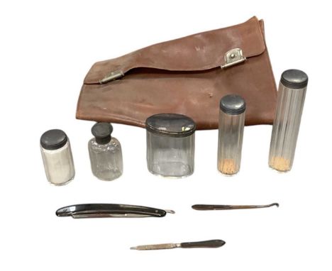 A leather travelling vanity case, with five hallmarked silver topped cut glass dressing table jars including two hat pin jars